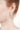 Close-up of a person wearing a leaf-shaped earring on a white background