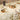 Dining table set with floral tablecloth, plates, and candles in a cozy indoor setting.
