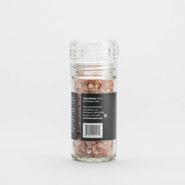 Glass container of pink Himalayan salt with a label on a white background