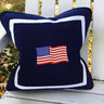 Navy blue pillow with American flag design on a white wooden surface