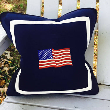 Navy blue pillow with American flag design on a white wooden surface