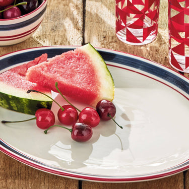 Slice of watermelon and cherries on a plate with a wooden background