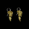 Gold fern leaf earrings on a black background