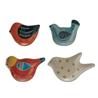 Four different stoneware bird shaped dishes, one is orange with black, one is blue with black, one is red with yellow and blue and one is white with green flowers