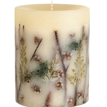 Off-white candle with forest themed botanicals embedded in the wax