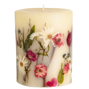 Off-white pillar candle with single wick featuring daisies, roses and green botanicals embedded into the wax