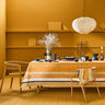 Dining room with a table set for a meal against a mustard yellow wall.