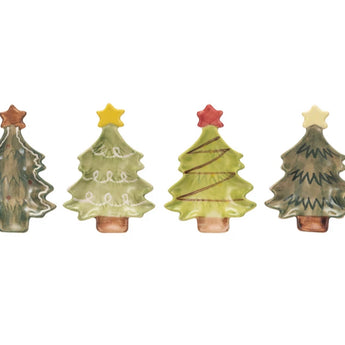 Four stoneware Christmas tree plates, one is dark green with a white outline and a bronze star, one is a light green with white swirled garland and a yellow star. One is light green with zig zag red garland and a red star. One is dark green with green detail outlining the shape of the pine tree, it has a white star.