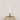 Hand-Forged Iron Bow Shaped Taper Holder, Antique Gold Finish Shown with lit candle in a vignette on a stack of books.