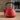 Red textured teapot with black handle on a wooden surface