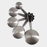 A set of stainless steel measuring cups with black handles, arranged in a fan shape against a light gray background. The metal cups are engraved with volume measurements including 1/4 cup, 1/3 cup, 1/2 cup, 1 cup, and 2 cups.