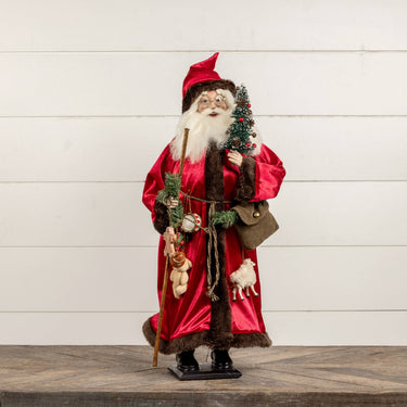 Ragon House Santa with Red Fur-Trimmed Robe. He is holding a tree and a staff. His belt is full of gifts