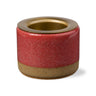 Cylindrical ceramic holder with red glaze and gold accents on a white background