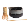 Ceramic teapot with wooden whisk and spoon on a white background