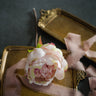 Pink flower arrangement on a gold tray with ribbons